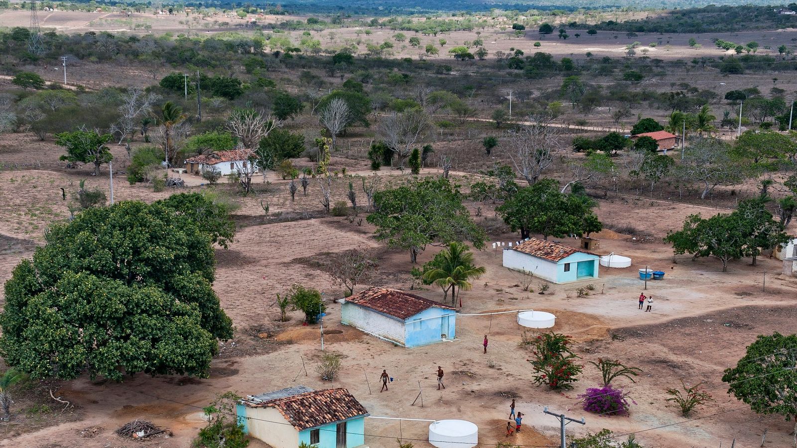 Vista aérea de área rural no semiárido baiano com casas esparsas e cisternas circulares brancas