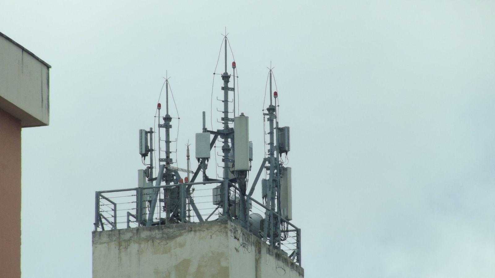 Antenas de telefonia celular instaladas no alto de um prédio, contra céu nublado