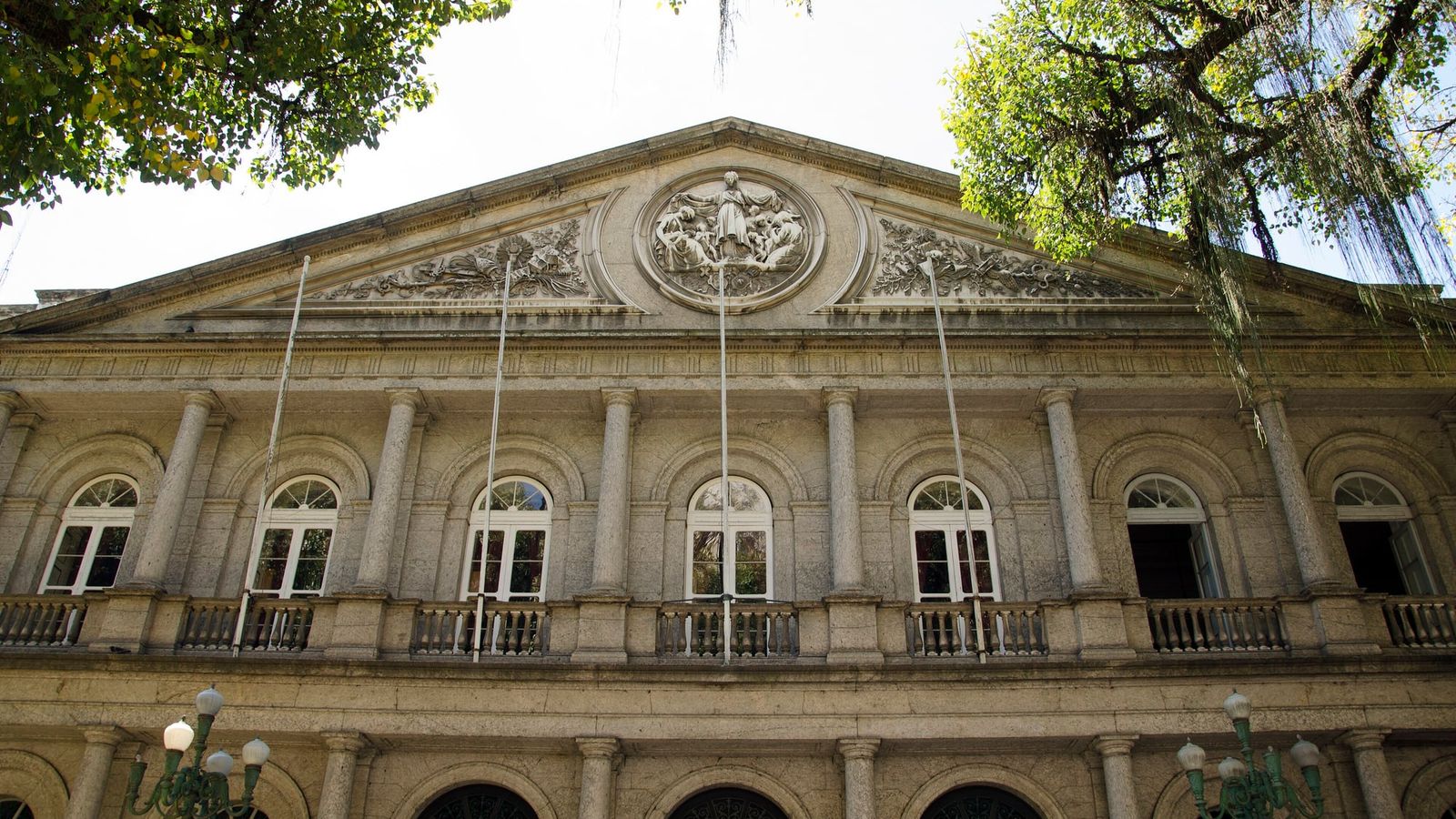Fachada neoclássica do hospital da Santa Casa de Misericórdia do Rio de Janeiro, com colunas e frontão, entre árvores